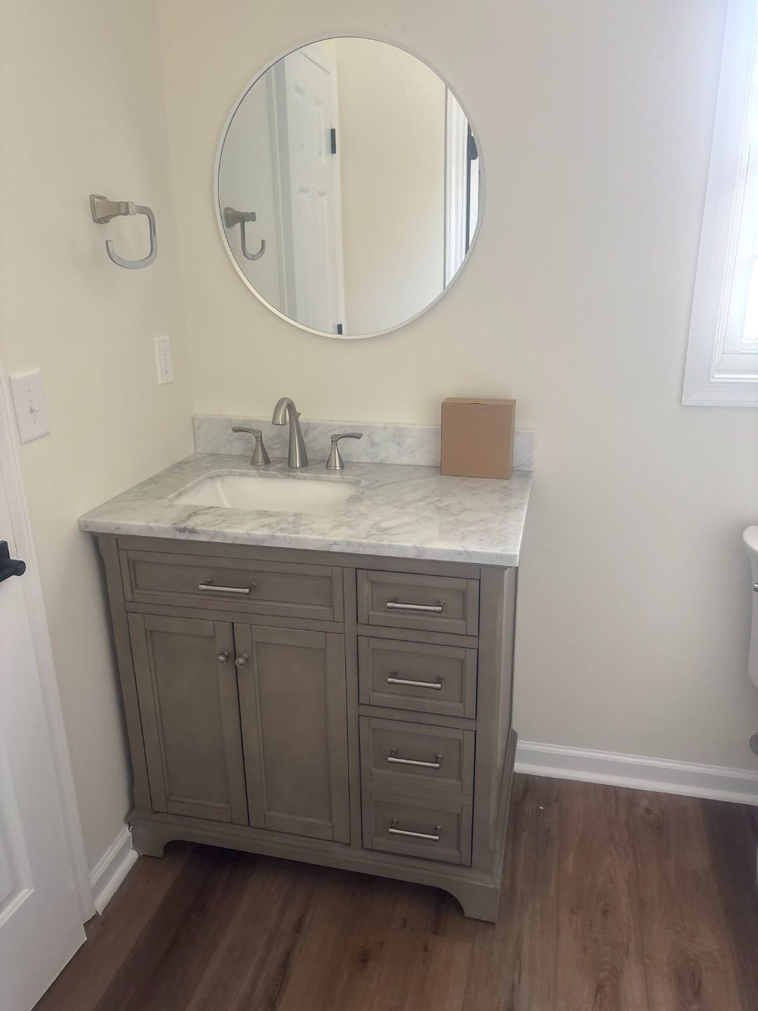 New bathroom vanity with marble countertop and round mirror